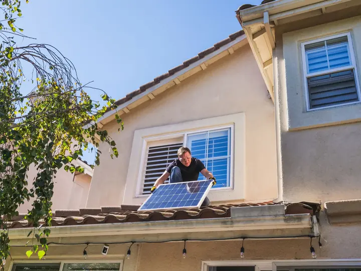 Poseur installant un panneau solaire sur le toit d'une maison